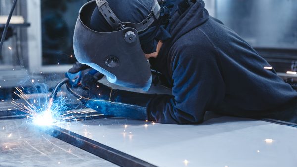 Welders On A Mission. Industrial labourer welding steel structure Male worker wearing helmet and gloves welding steel